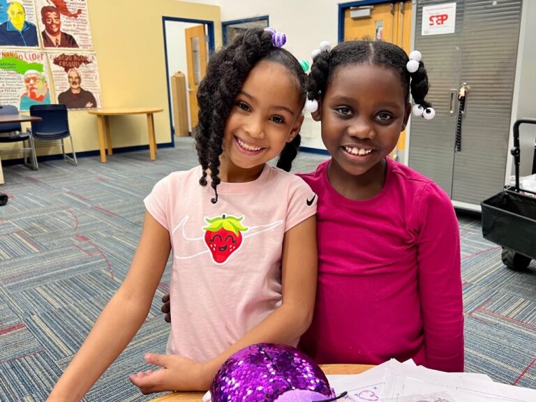 Two girls smile at a Susan Sargen Student Enterprise Program (StEP) store at their school